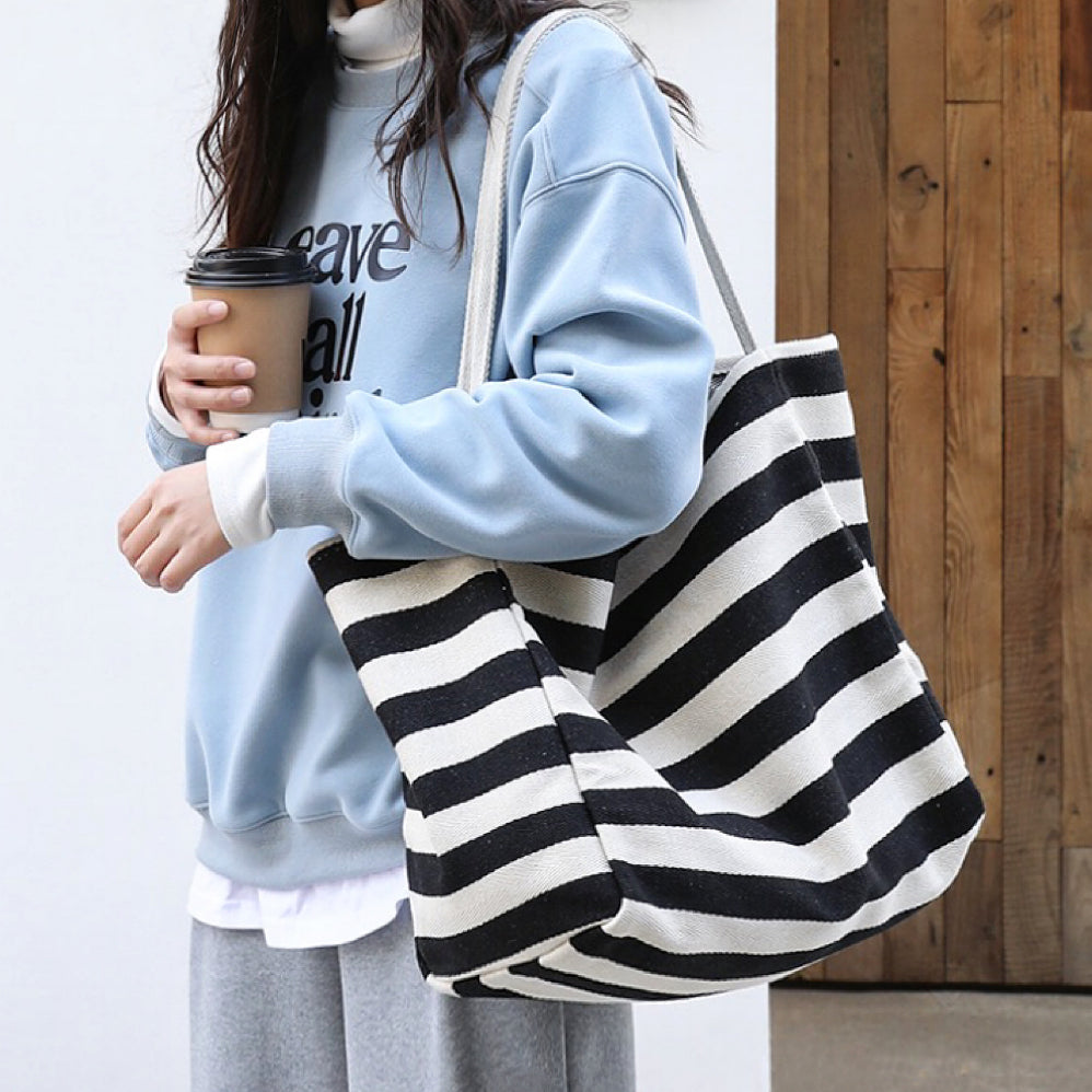 Model carrying a black striped tote bag on shoulder, easy for commuting and weekends.