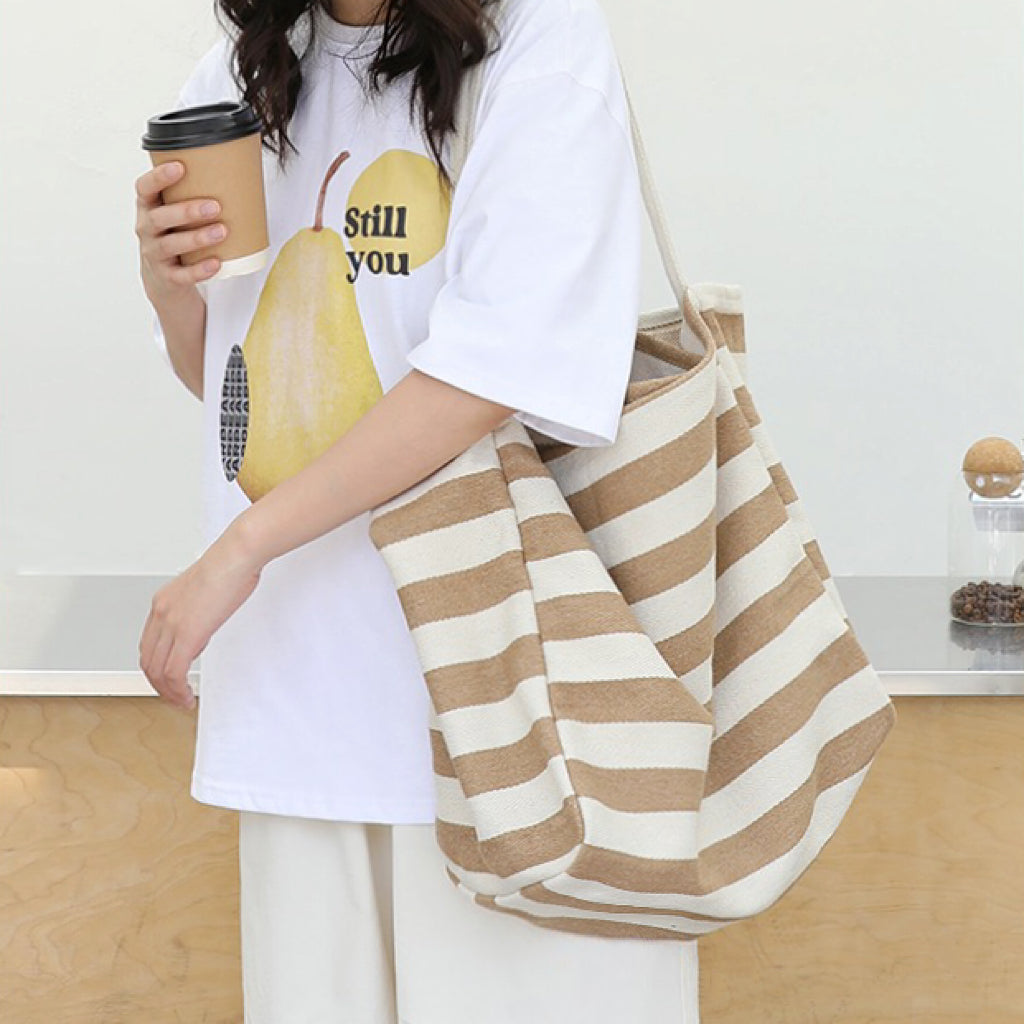 Model carrying a khaki striped tote bag on shoulder, great for daily carry and travel.
