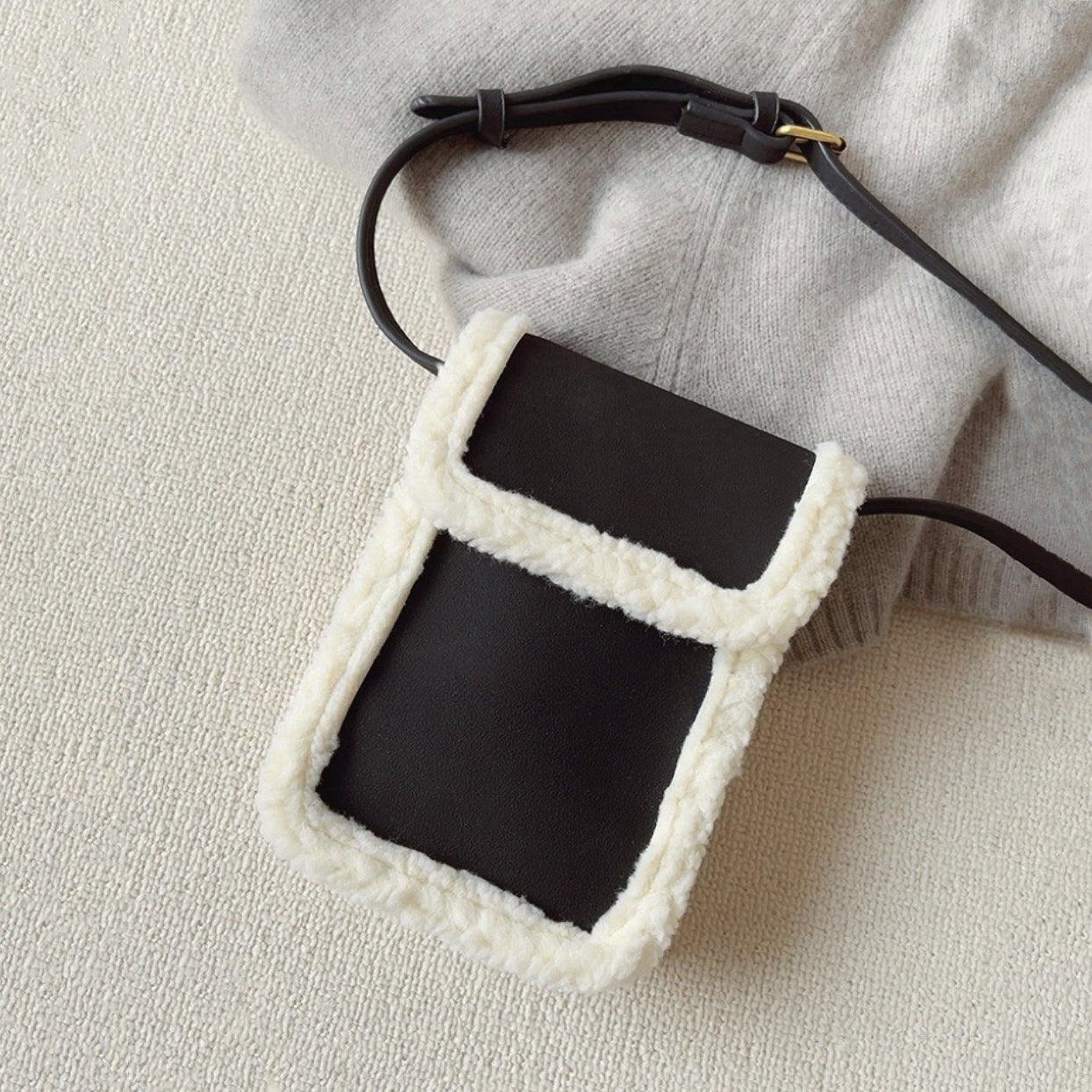 Flat lay of  Suede Crossbody Bag With Plush Trim in black, great for everyday carry and travel.