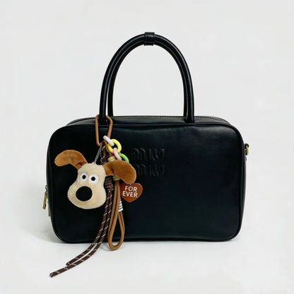 Super Dog bag charm hanging on a black handbag.