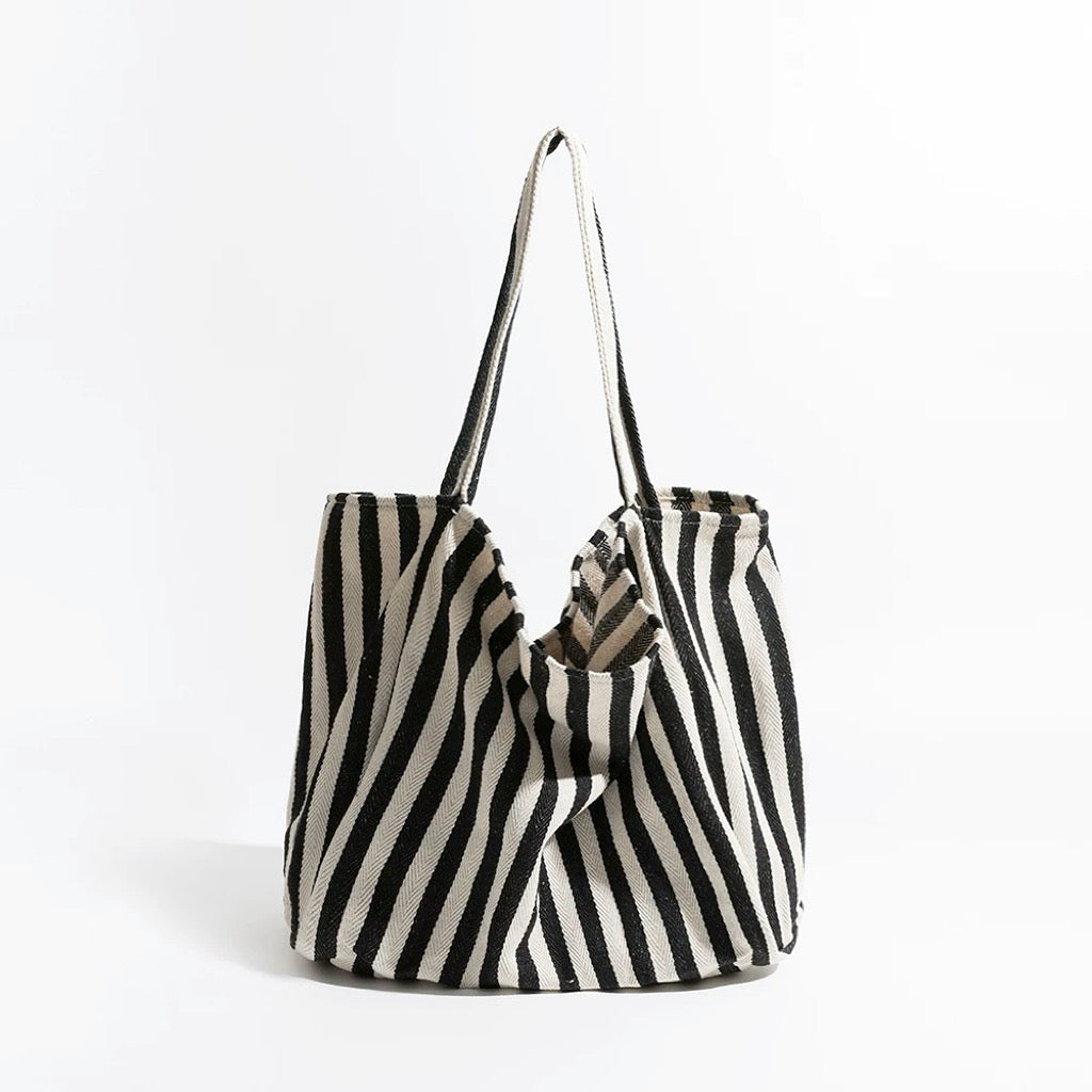 Black and white thin stripe canvas tote bag with shoulder strap and open top.