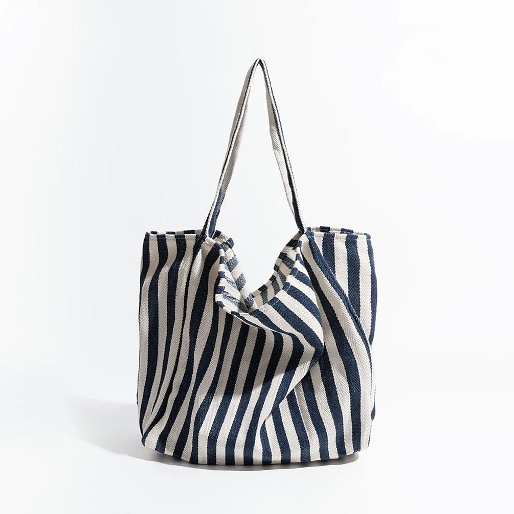 Front view of navy blue and white striped canvas tote, classic nautical look suited for outdoor picnics and boat trips.