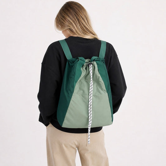 Back view of a model wearing the green two-tone ultralight 2-way drawstring backpack.