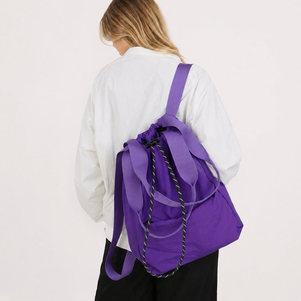 Model wearing the classic black 2-way drawstring backpack over one shoulder as a tote.