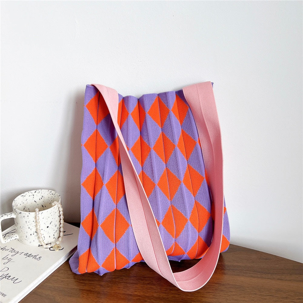 Close-up of a purple and orange argyle knitted tote bag with a pink shoulder strap.