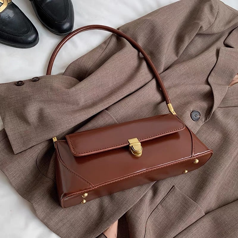 Angled view of Brown vintage baguette shoulder bag made of glossy PU leather.