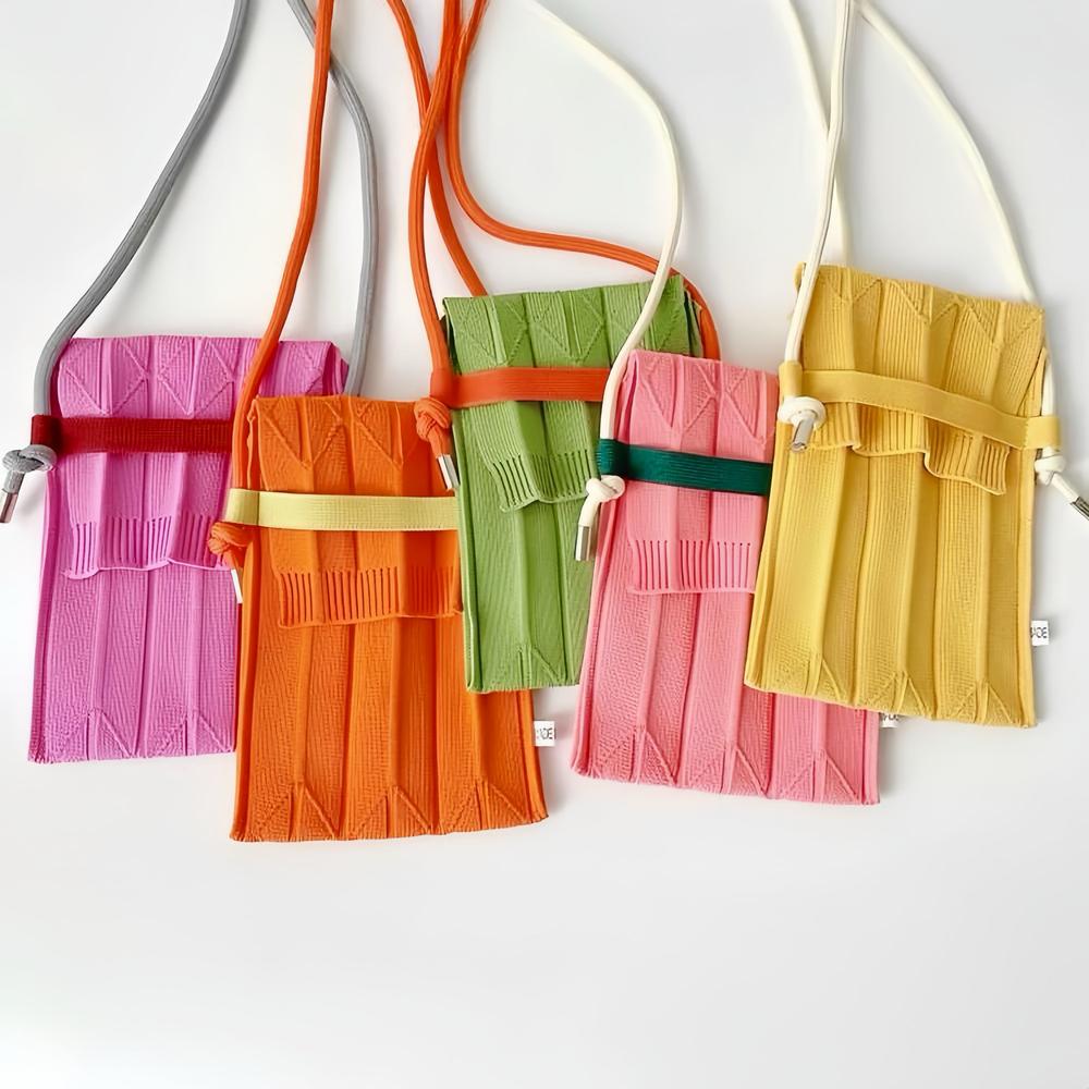 Front view of Five vivid knit polyester mini bags in pink, orange, green, and yellow with adjustable crossbody straps.