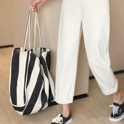 Model carrying a black and white Wide Stripe Canvas Tote Bag handheld, ideal for errands and gifting.