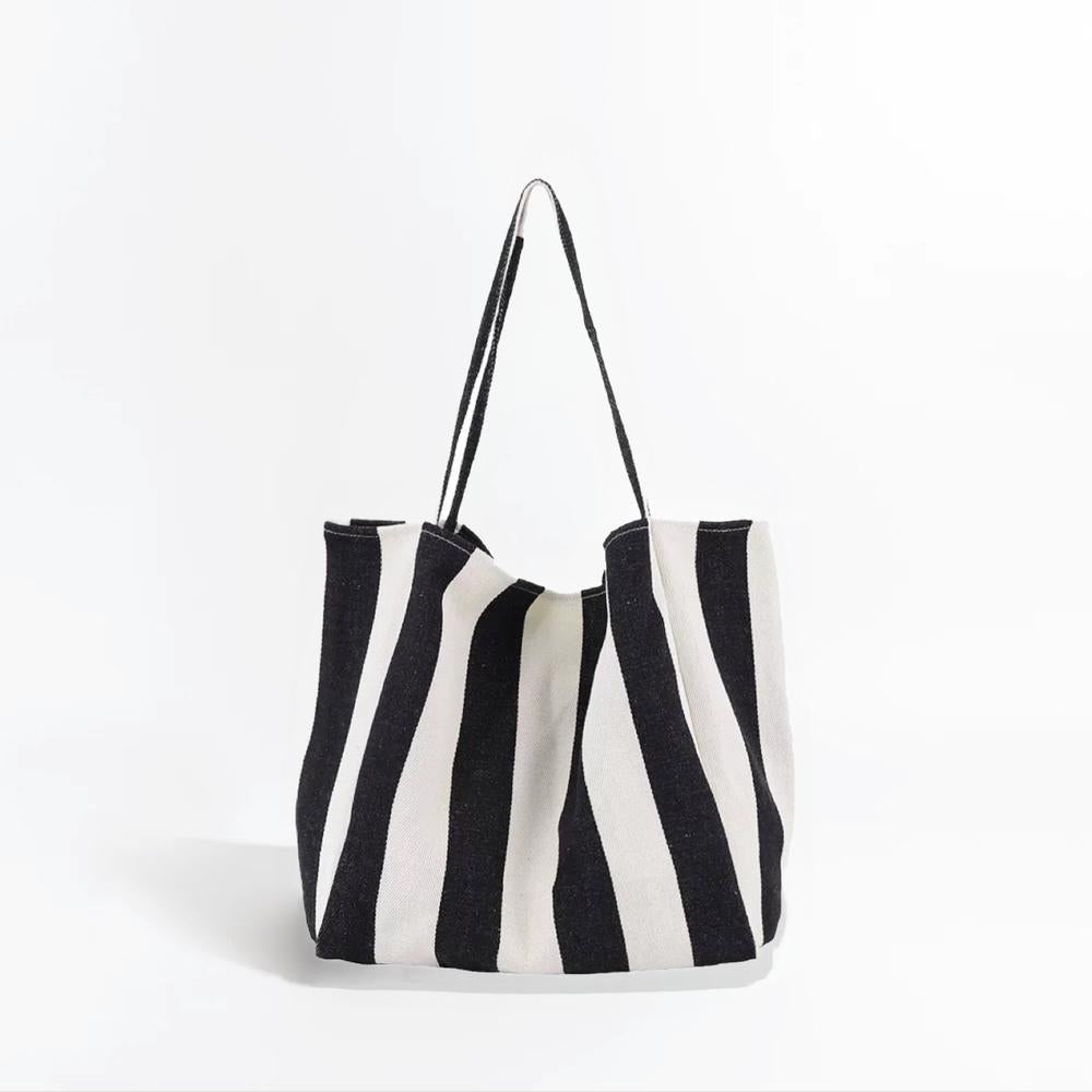 Angled view of Black and white wide stripe canvas tote bag with shoulder straps and an open top.