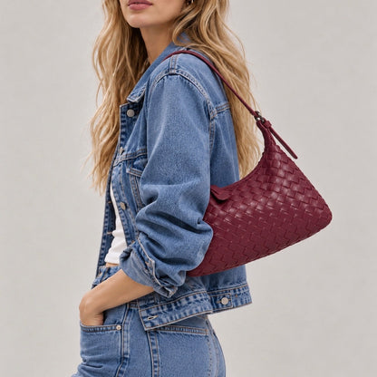 Model carrying a burgundy woven leather shoulder purse with white top.