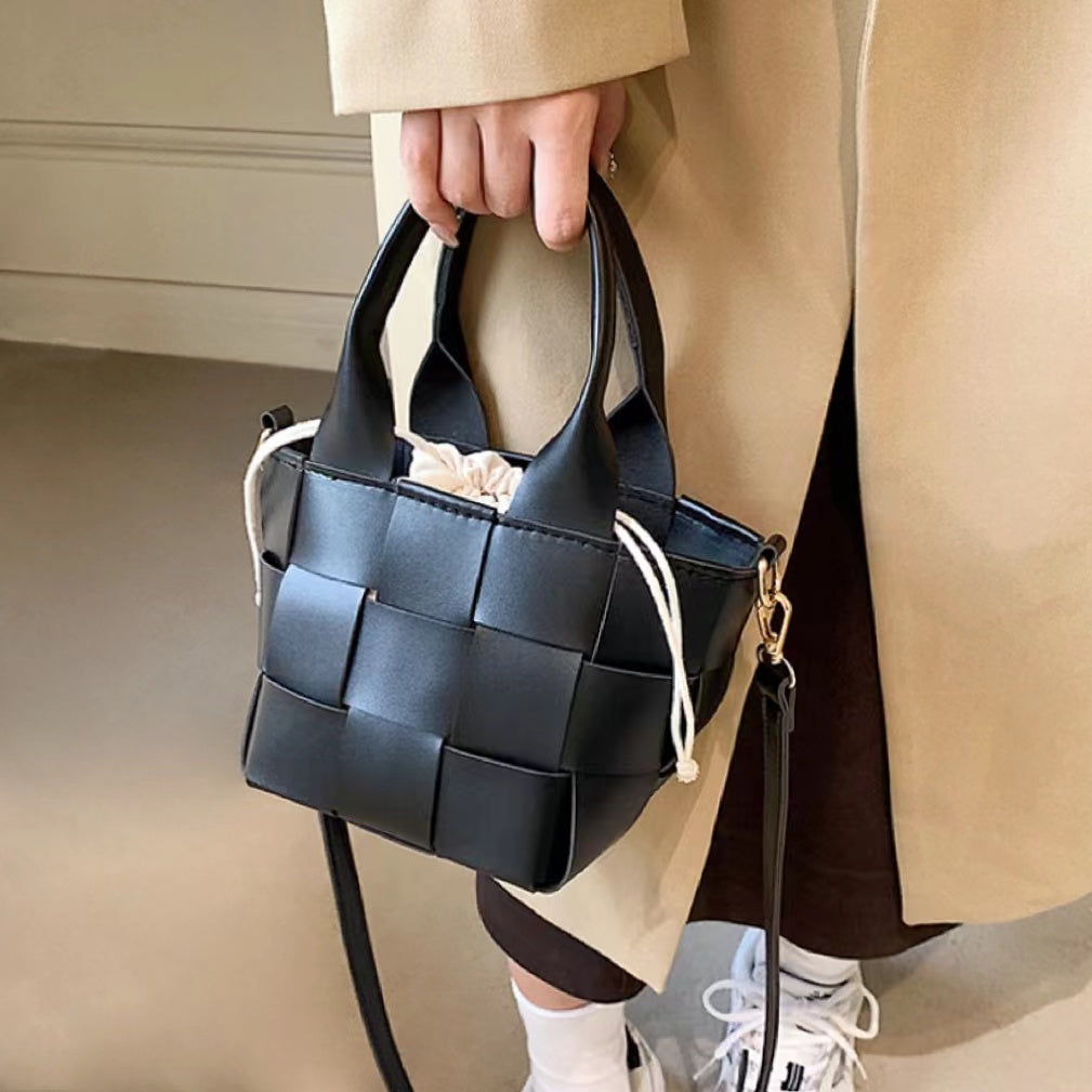 Model carrying a black Woven Leather Mini Basket Bag handheld, easy for commuting and weekends.