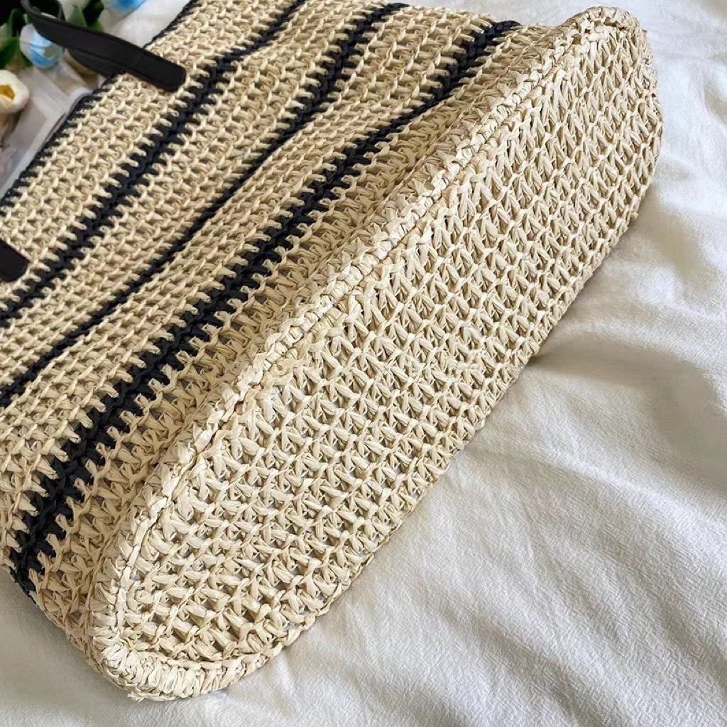 Close-up of Woven straw tote bag with black stripes, showcasing the bottom.