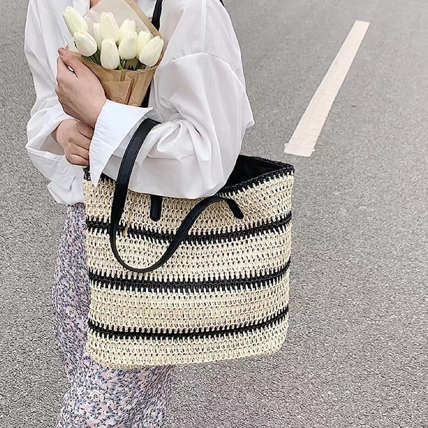 Model carring a Woven Straw Tote Bag with Black Stripe, great for everyday carry and travel.