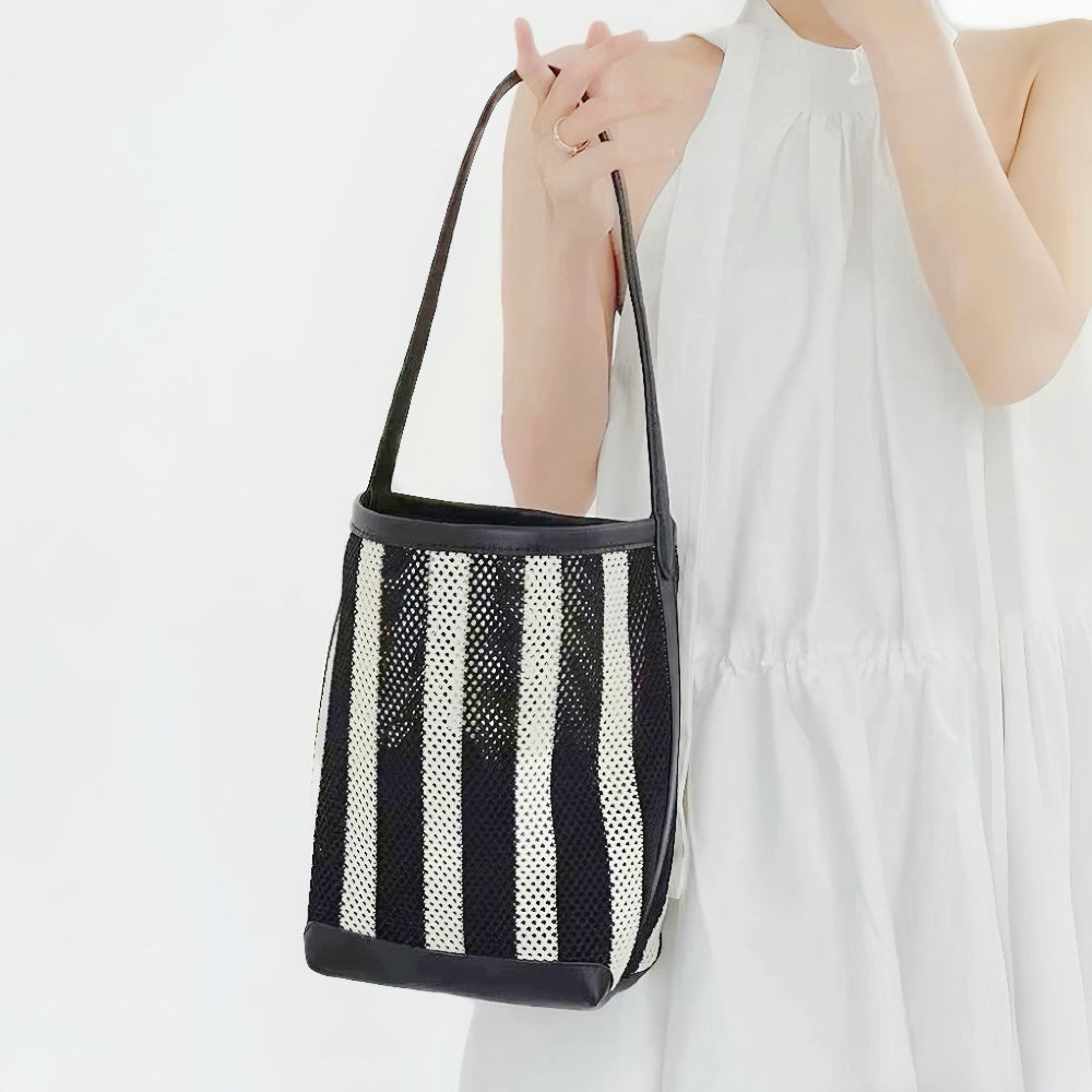 Model holding the small woven striped raffia bucket bag.